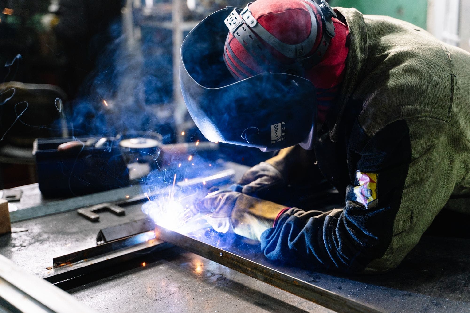 Welder fabricating metal indoors with bright sparks