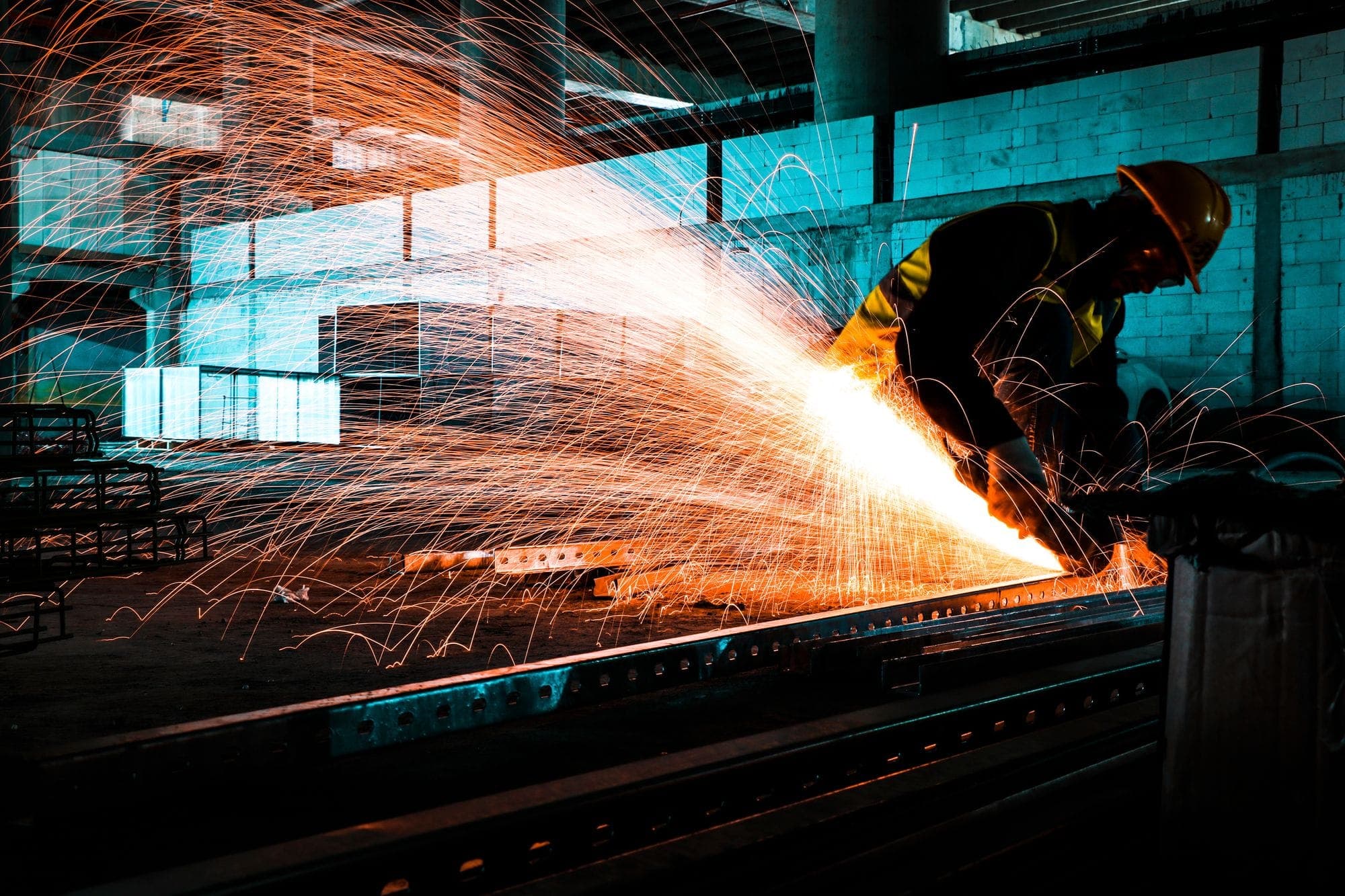 Worker cutting steel with an angle grinder, sparks flying